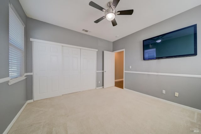 unfurnished bedroom with baseboards, visible vents, a ceiling fan, carpet, and a closet