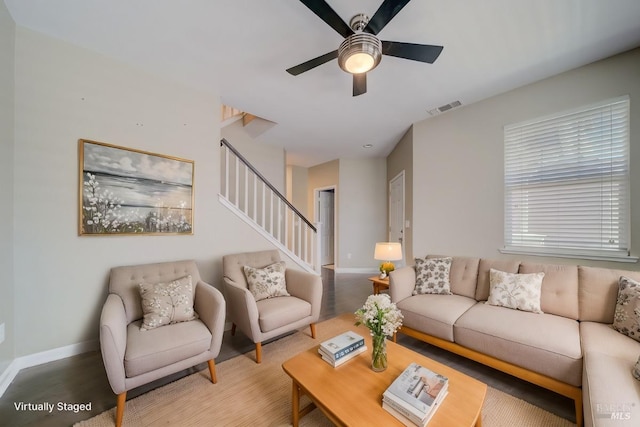 living room featuring baseboards, stairs, visible vents, and a ceiling fan