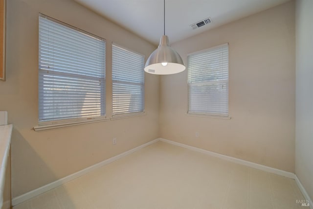 empty room featuring baseboards and visible vents