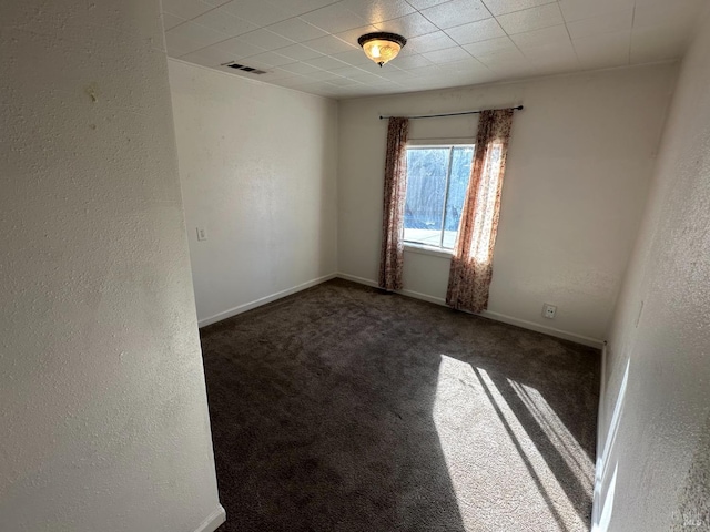 carpeted empty room featuring baseboards, visible vents, and a textured wall