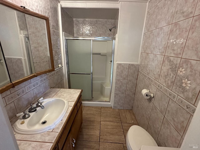 full bathroom featuring toilet, vanity, a shower stall, and tile walls