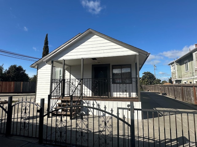 bungalow-style home with covered porch and a fenced front yard