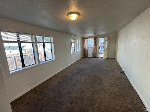 carpeted empty room with a textured wall and baseboards