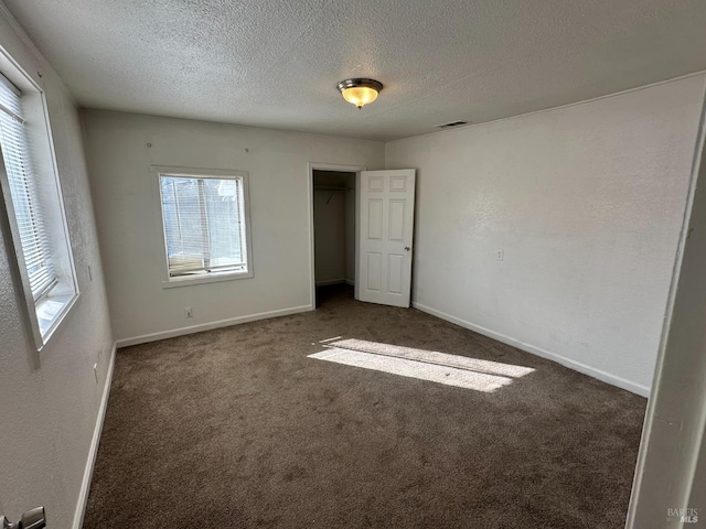 unfurnished bedroom featuring baseboards, visible vents, a textured ceiling, carpet floors, and a closet