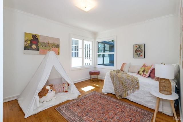 bedroom with ornamental molding, wood finished floors, and baseboards