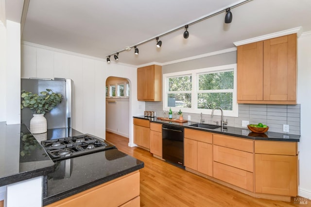 kitchen featuring arched walkways, dishwasher, freestanding refrigerator, stovetop, and a sink