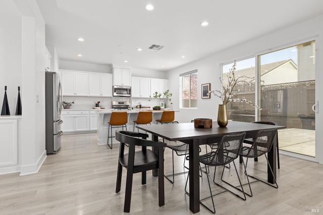 dining area featuring light wood finished floors, visible vents, and recessed lighting