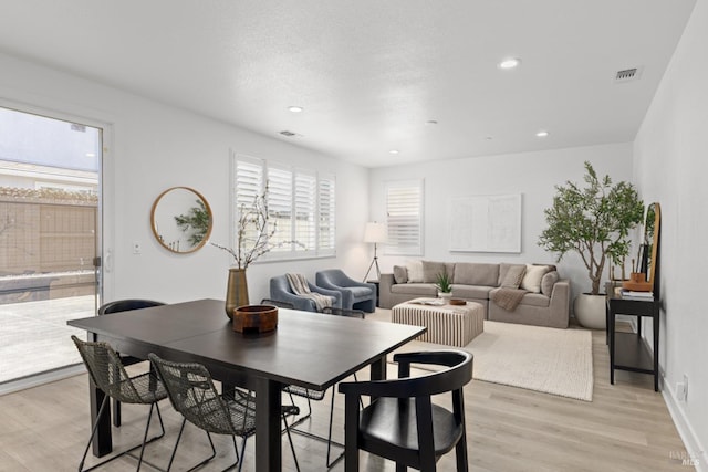 dining space with light wood-type flooring, visible vents, a textured ceiling, and recessed lighting