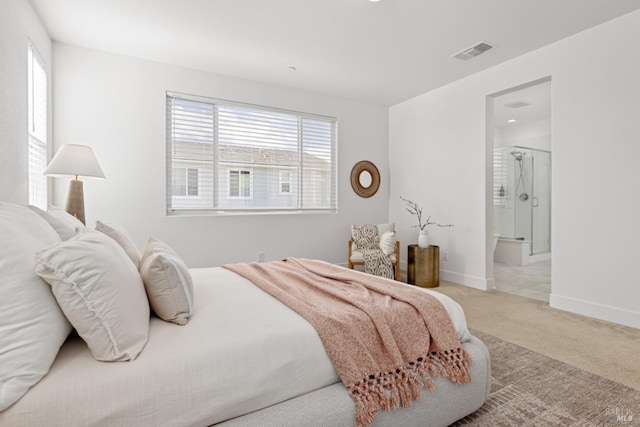 carpeted bedroom with ensuite bath, visible vents, and baseboards