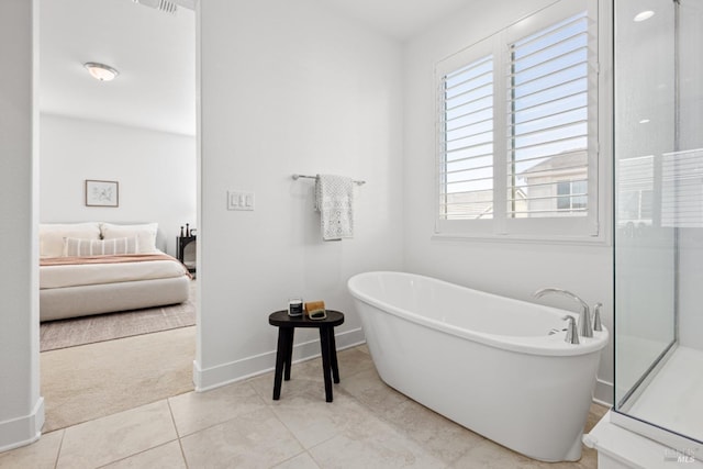 bathroom with baseboards, tile patterned floors, ensuite bathroom, a freestanding tub, and a shower stall