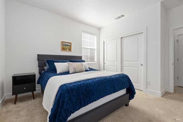 bedroom featuring light colored carpet, a closet, visible vents, and baseboards