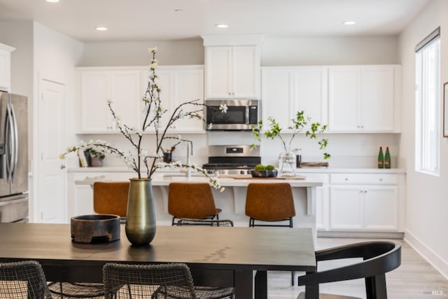 kitchen with stainless steel appliances, recessed lighting, light countertops, white cabinets, and light wood-type flooring