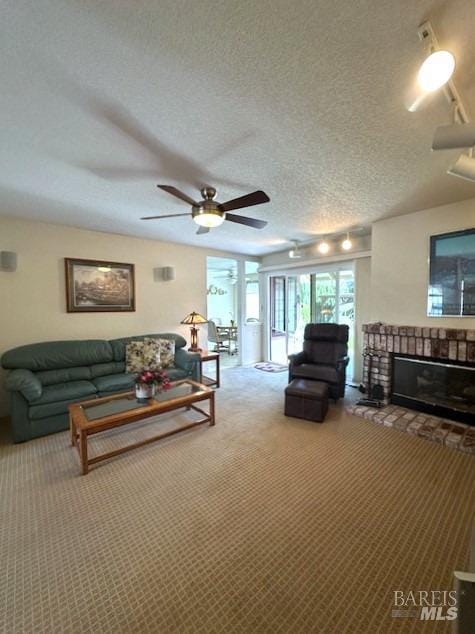 living area featuring a textured ceiling, carpet floors, a brick fireplace, and a ceiling fan