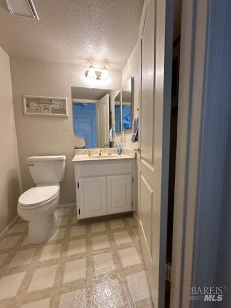 bathroom featuring toilet, baseboards, a textured ceiling, and vanity