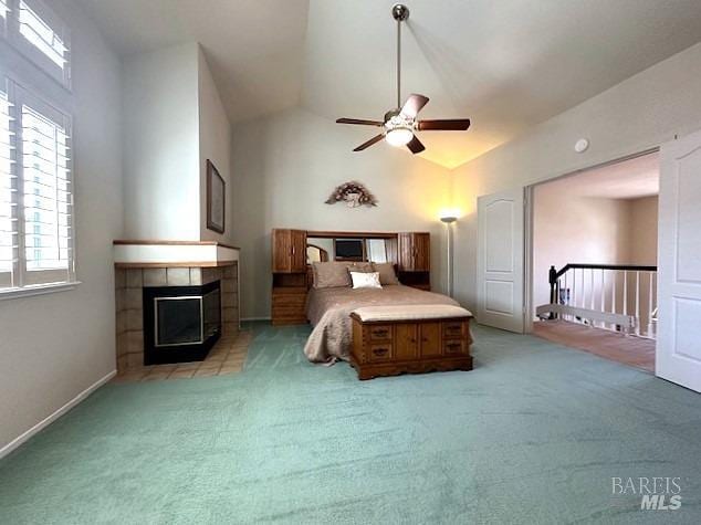 bedroom with high vaulted ceiling, light carpet, ceiling fan, and a tiled fireplace