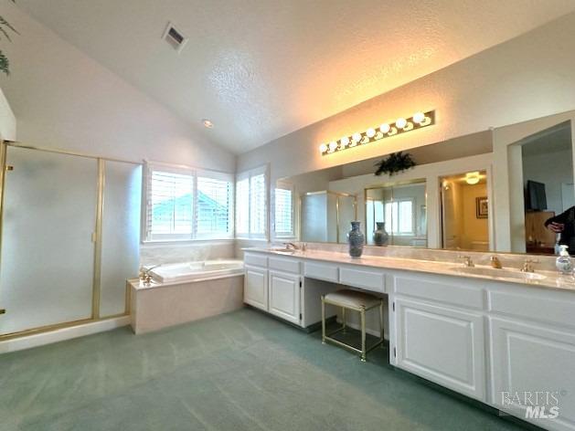 full bathroom with double vanity, a stall shower, visible vents, vaulted ceiling, and a sink