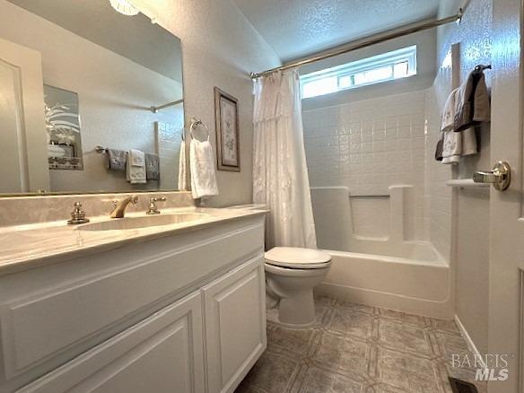 bathroom featuring shower / bath combo, a textured ceiling, toilet, and vanity