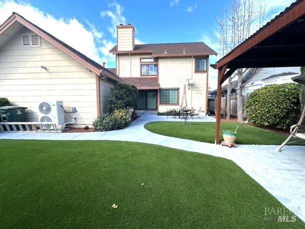 rear view of property featuring a chimney, a patio, and a yard