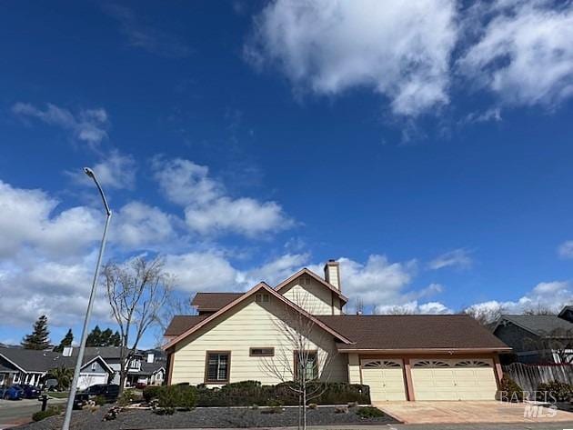 view of front of house with driveway, a chimney, and an attached garage