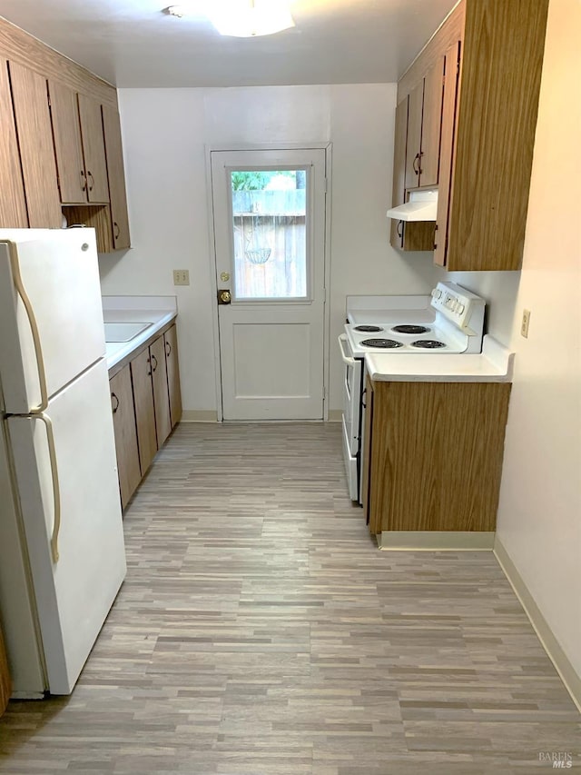 kitchen featuring under cabinet range hood, white appliances, baseboards, light countertops, and brown cabinetry