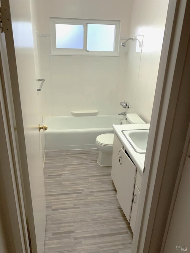 bathroom featuring toilet, vanity, wood finished floors, and bathing tub / shower combination