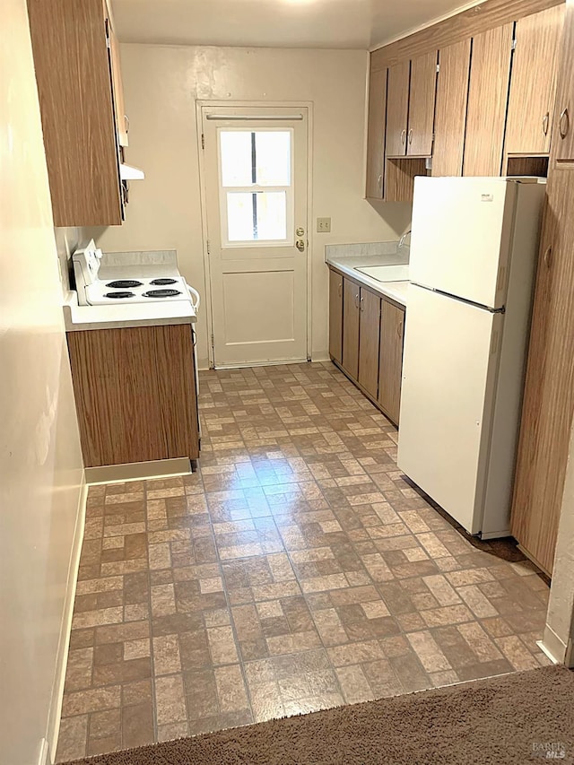 kitchen featuring brick floor, white appliances, light countertops, and a sink