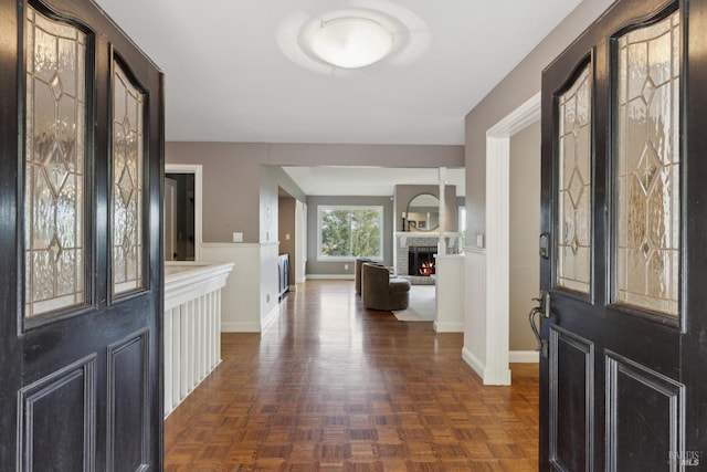 foyer entrance with a brick fireplace and a wainscoted wall