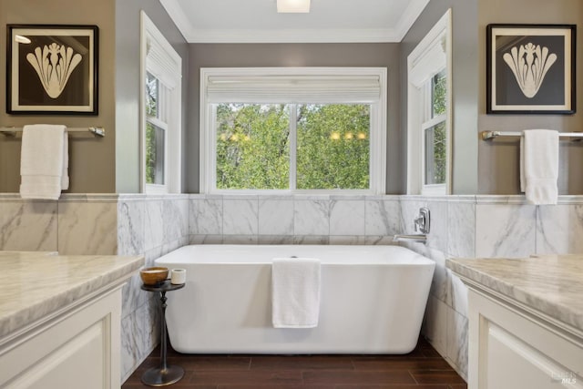 bathroom featuring ornamental molding, wood tiled floor, vanity, a freestanding tub, and tile walls