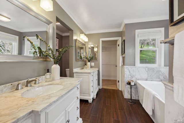 full bath featuring two vanities, wood finished floors, a sink, a bathtub, and tile walls