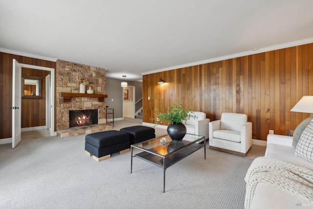 living room featuring ornamental molding, wood walls, a fireplace, and light colored carpet