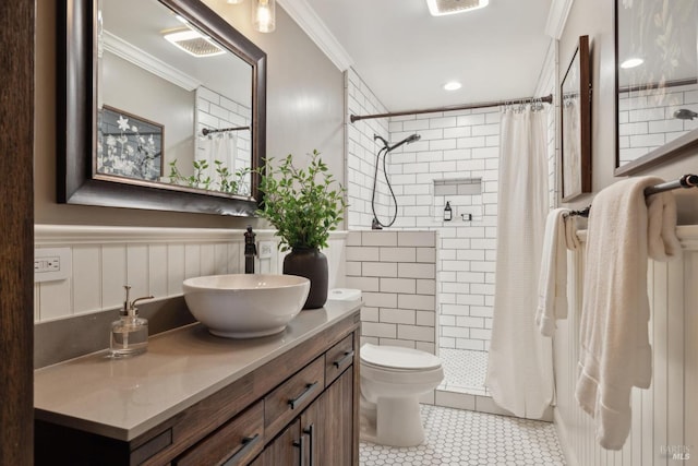 bathroom with a wainscoted wall, a tile shower, and crown molding