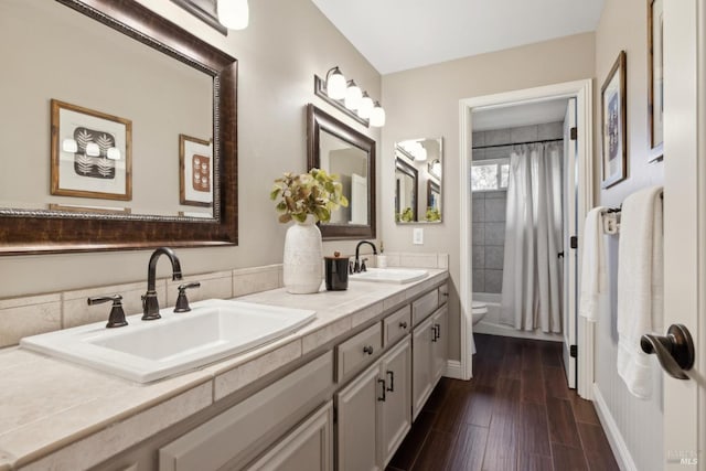 full bathroom featuring curtained shower, a sink, toilet, and wood finished floors