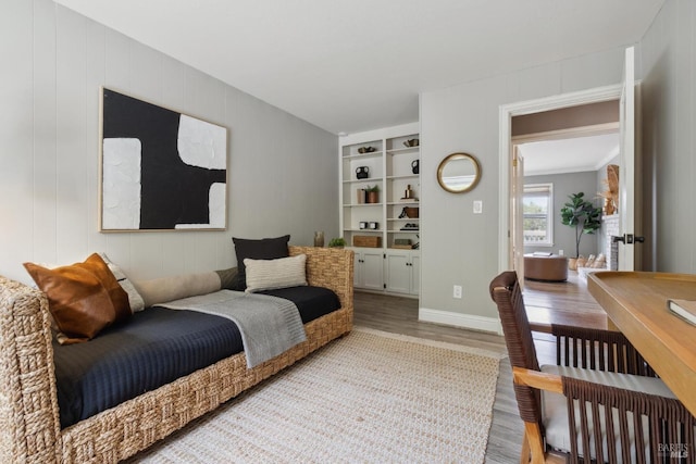 living room featuring built in shelves, wood finished floors, and baseboards