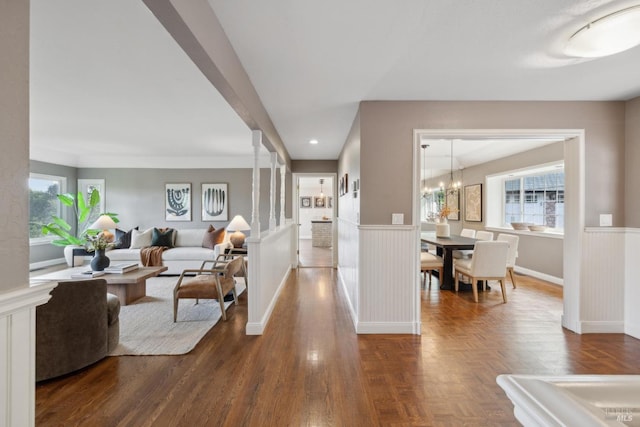 living area with parquet floors, a healthy amount of sunlight, and wainscoting