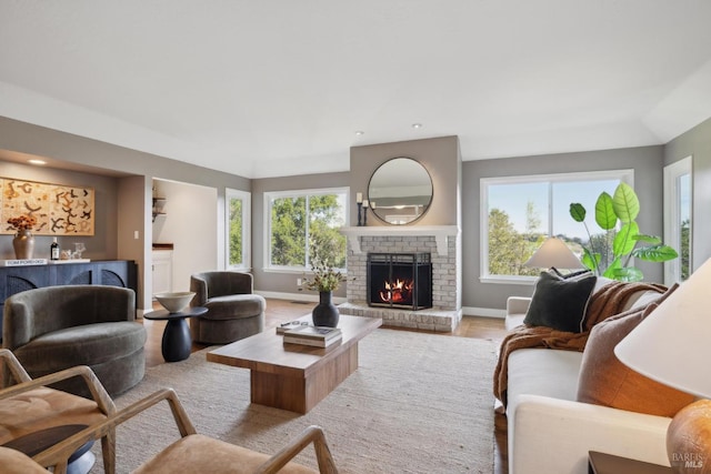 living area with a fireplace, baseboards, and wood finished floors