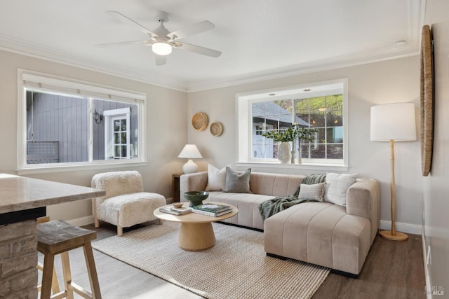 living area with baseboards, ornamental molding, ceiling fan, and wood finished floors