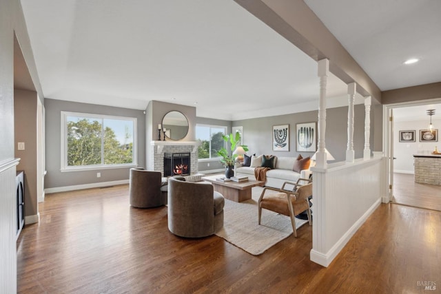 living room featuring a lit fireplace, baseboards, wood finished floors, and recessed lighting