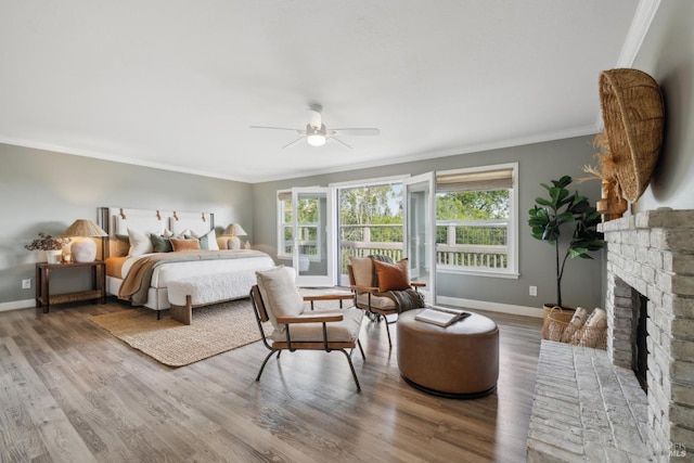 bedroom featuring a fireplace, baseboards, crown molding, and wood finished floors