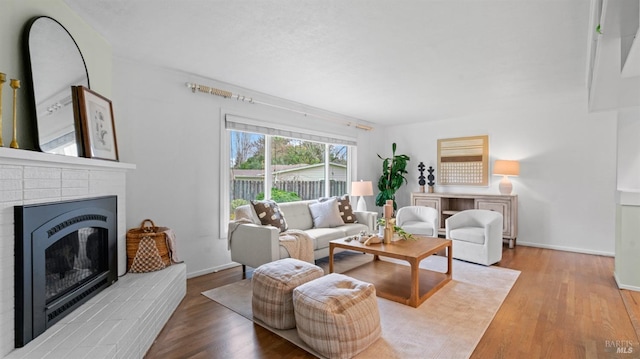 living room with a fireplace, wood finished floors, and baseboards