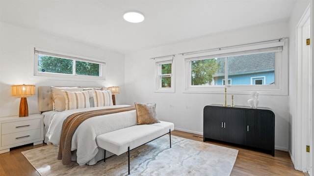 bedroom with multiple windows, wood finished floors, and baseboards