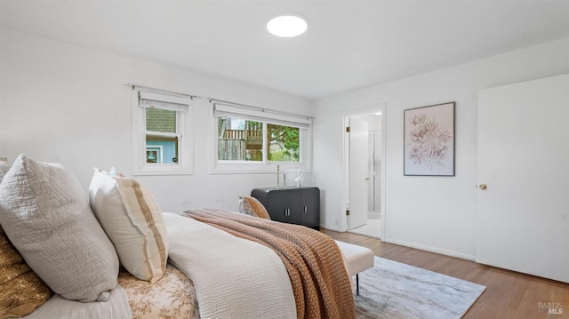 bedroom featuring ensuite bath and wood finished floors