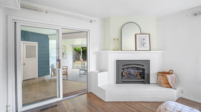 living area featuring french doors, visible vents, a fireplace, and wood finished floors