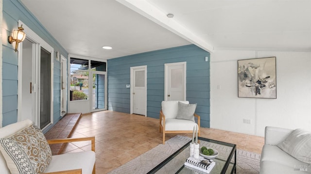 living area with tile patterned flooring and beam ceiling