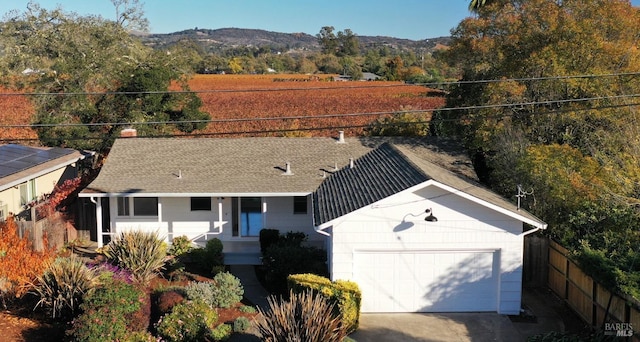 ranch-style home featuring a shingled roof, fence, and a mountain view