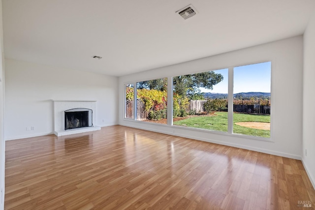 unfurnished living room with a wealth of natural light, visible vents, a fireplace, and light wood-style flooring