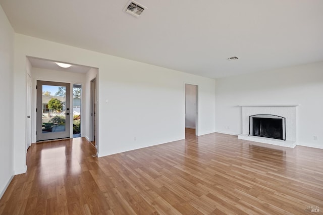 unfurnished living room featuring visible vents, a fireplace, light wood-style flooring, and baseboards