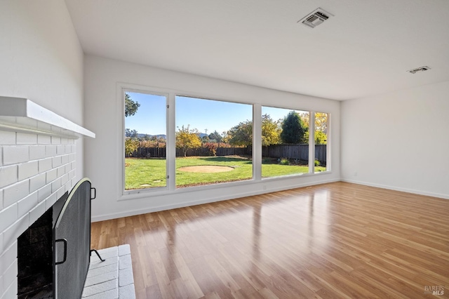 unfurnished living room featuring light wood-style floors, a fireplace with flush hearth, and visible vents