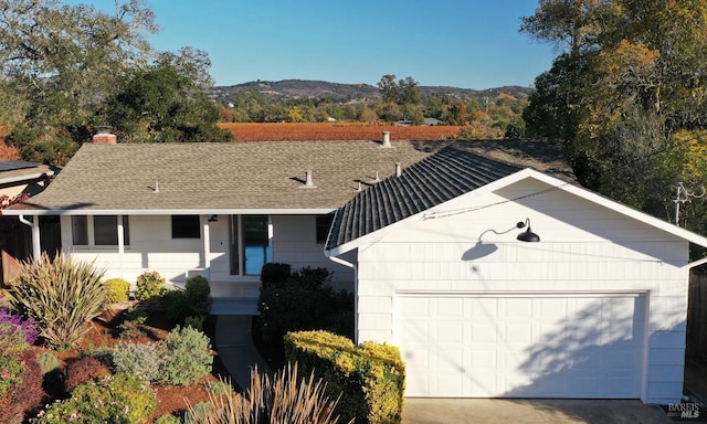 view of front of property featuring a garage, concrete driveway, a shingled roof, and a mountain view