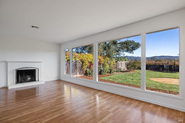 unfurnished living room with baseboards, a fireplace, visible vents, and wood finished floors