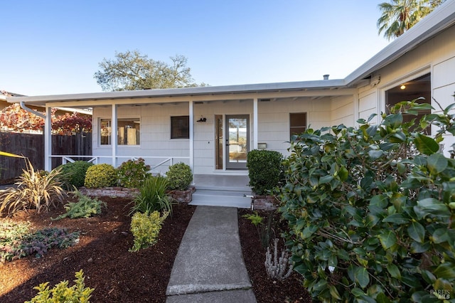 doorway to property with a porch and fence